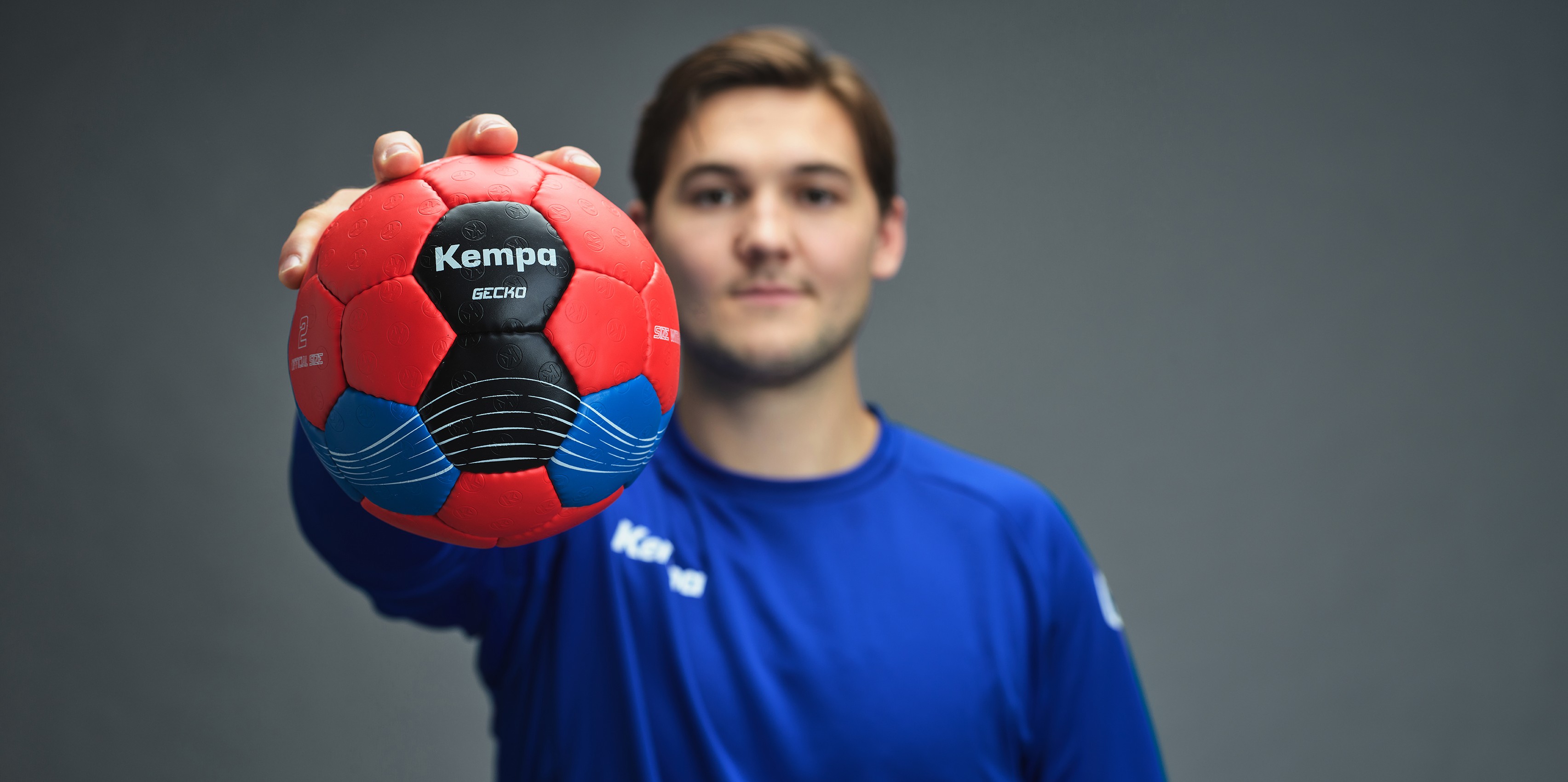 Ein Handballer hält einen Gecko Kempa Handball in die Kamera