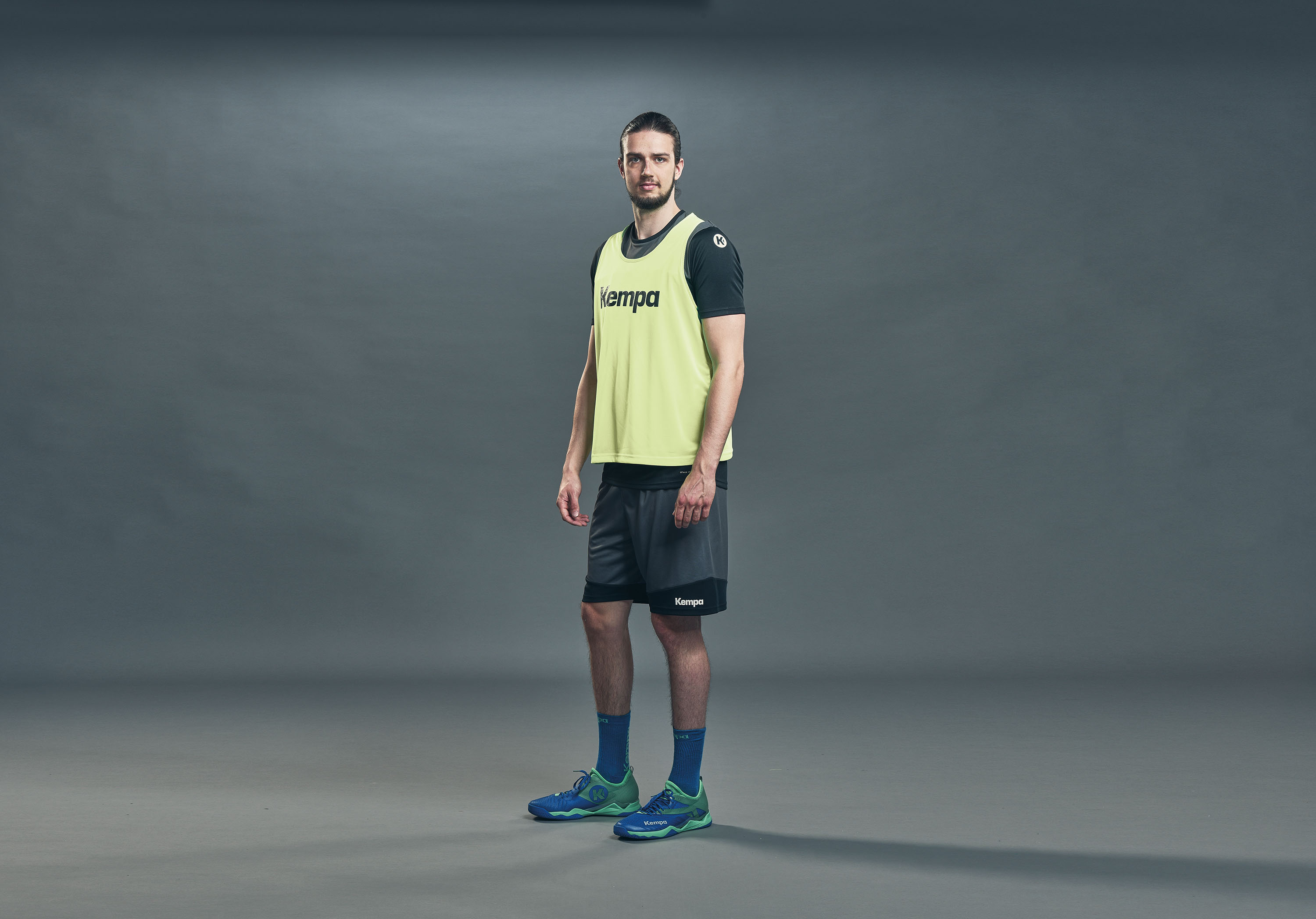 Ein junger Mann trägt ein gelbes Leibchen der Marke Kempa